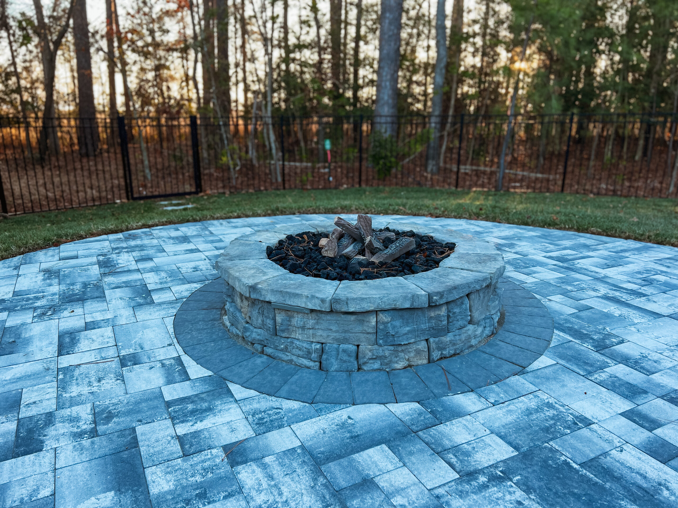 fire pit in backyard surrounded by paver patio
